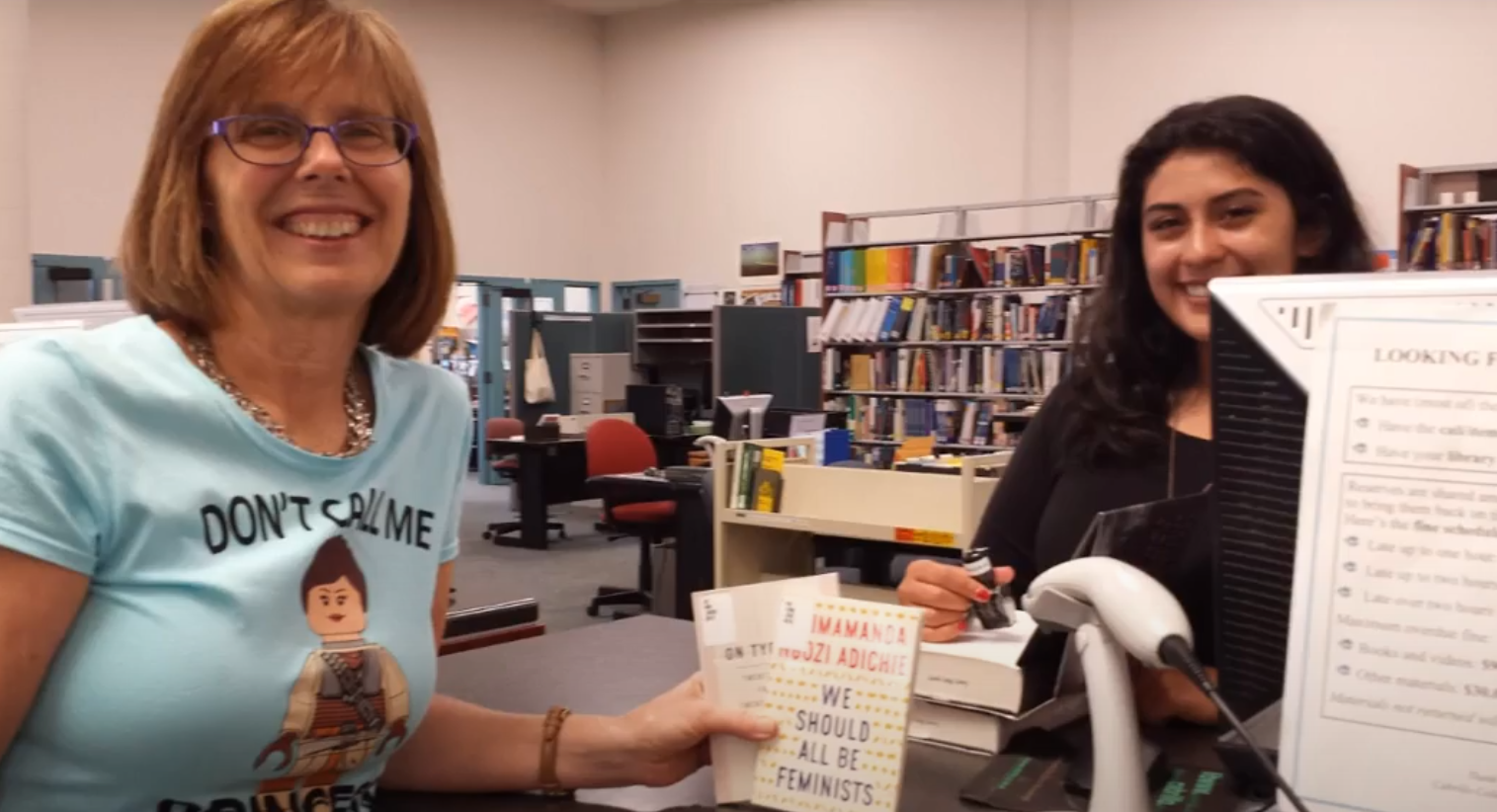 Smiling librarian and library staff at the checkout desk